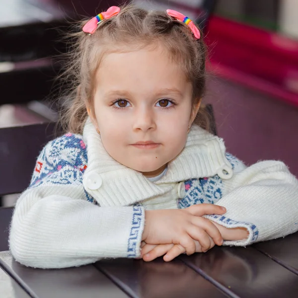 Emotionele meisje aan een tafel in een café. Schattig klein meisje zittend in openlucht restaurant op zomerdag. kind in een café zijn bestelling wachten. — Stockfoto