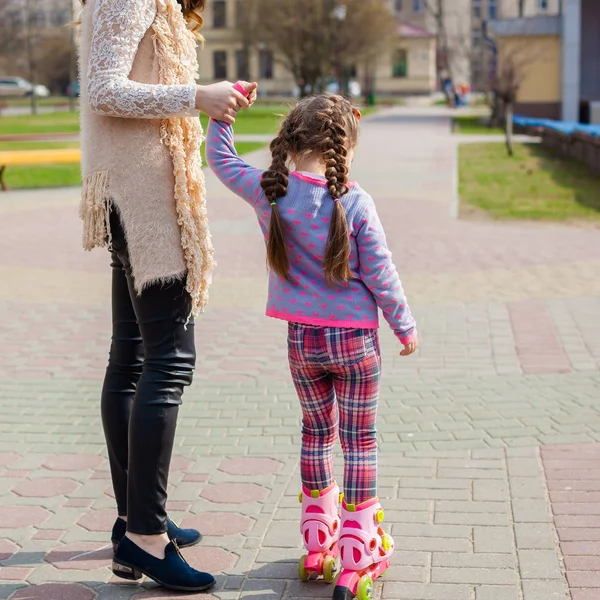 Maman et fille roulent en patins à roulettes. Une fille apprend à patiner et tombe. Maman enseigne fille à monter sur des rouleaux — Photo