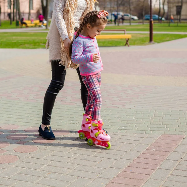 Mamá y su hija montan patines. Chica aprendiendo a patinar, y cae. Mamá enseña a su hija a montar en rodillos —  Fotos de Stock