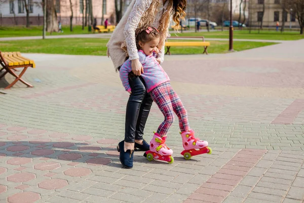 Mamá y su hija montan patines. Chica aprendiendo a patinar, y cae. Mamá enseña a su hija a montar en rodillos —  Fotos de Stock