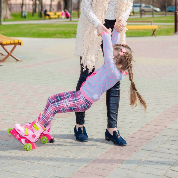 Mãe e filha andam de patins. Menina aprendendo a patinar, e cai. Mãe ensina filha a montar em rolos — Fotografia de Stock