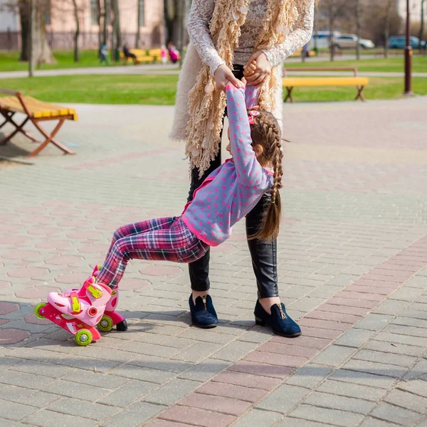 Moeder en dochter rijden op rolschaatsen. Meisje leren rolschaatsen, en watervallen. Moeder leert dochter om te rijden op rollen — Stockfoto