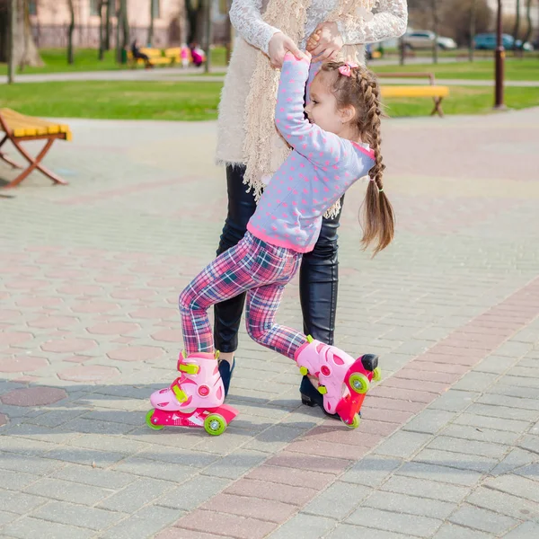 妈妈和女儿骑在旱冰鞋上。女孩学习轮滑，和瀑布。妈妈教女儿骑辊 — 图库照片
