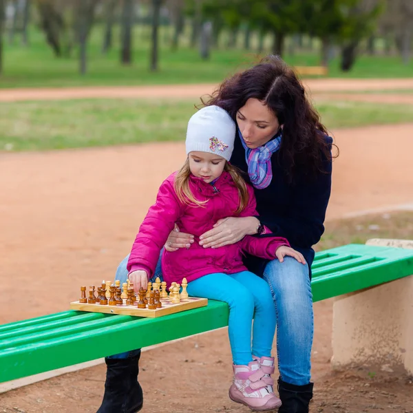 Mère et fille jouant aux échecs sur un banc dans le parc — Photo