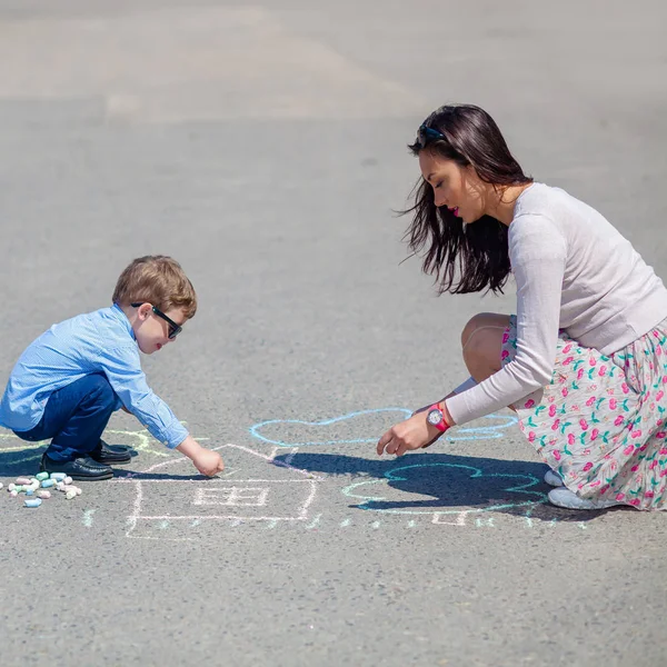 Mutter und kleiner Sohn zeichnen mit Kreide auf der Straße. — Stockfoto