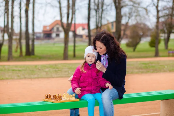 Madre e figlia che giocano a scacchi su una panchina nel parco — Foto Stock