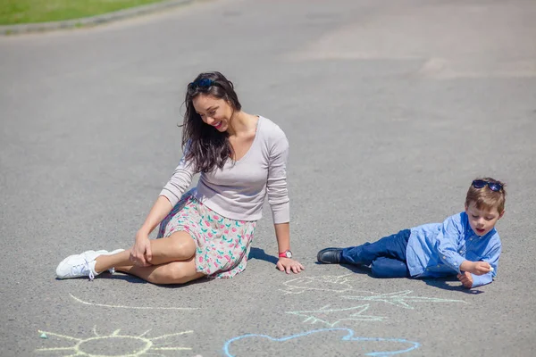 Mamá e hijo pequeño están pintando con lápices de colores en la carretera . —  Fotos de Stock