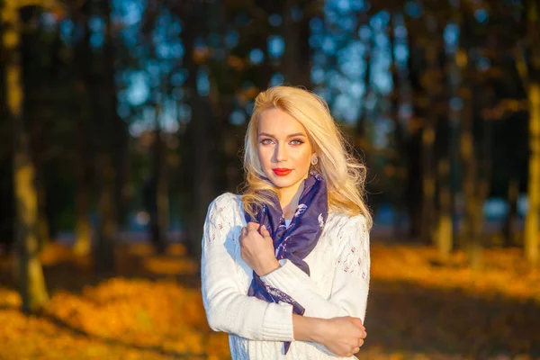 Beautiful blonde girl in a white sweater freezing in the park — Stock Photo, Image