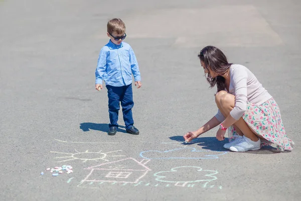 Mamá e hijo pequeño están pintando con lápices de colores en la carretera . —  Fotos de Stock