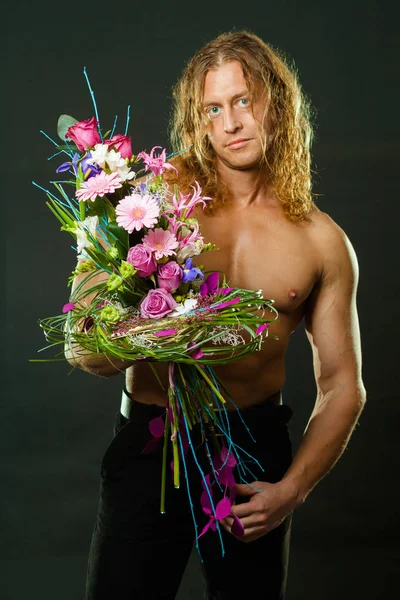 留着长头发的男子气概肌肉男手里拿着一束鲜花设计 — 图库照片
