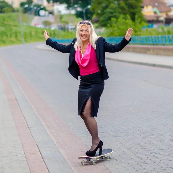 Senior obchodní žena baví na skateboardu venku — Stock fotografie
