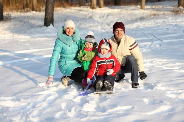 Czteroosobowa rodzina ma zabawy na śniegu w zimie — Zdjęcie stockowe