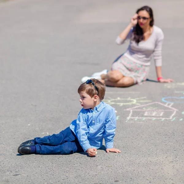 Мама и маленький сын рисуют мелом на дороге . — стоковое фото