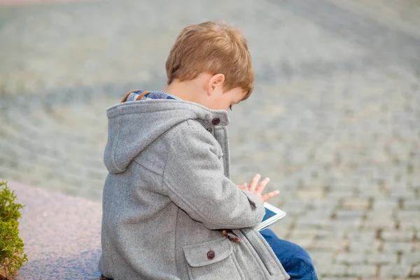 Petit garçon utilise une tablette à l'extérieur — Photo