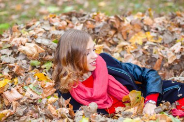 neşeli pozitif dreamy kız parkta yaprakları arasında yalan