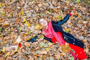 neşeli pozitif dreamy kız parkta yaprakları arasında yalan