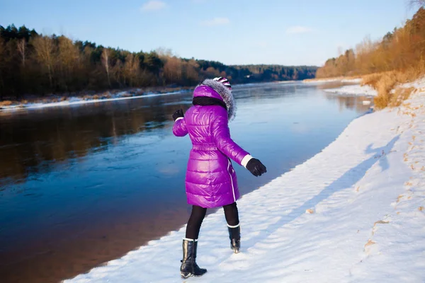 Adolescent fille marche en hiver sur la rive d'une rivière gelée — Photo