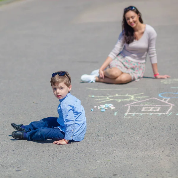 Mamá e hijo pequeño están pintando con lápices de colores en la carretera . — Foto de Stock