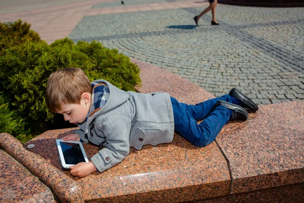 Petit garçon utilise une tablette à l'extérieur — Photo