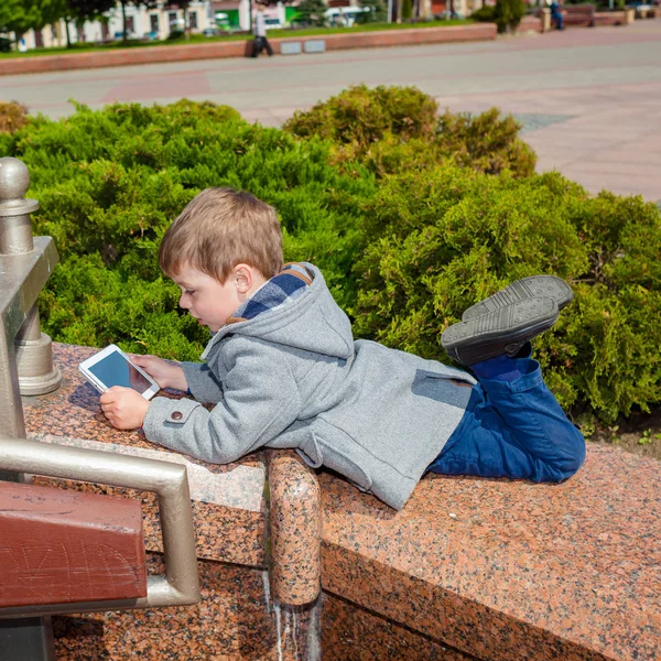 Jongetje maakt gebruik van een tablet buitenshuis — Stockfoto