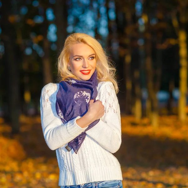 Beautiful blonde girl in a white sweater freezing in the park — Stock Photo, Image