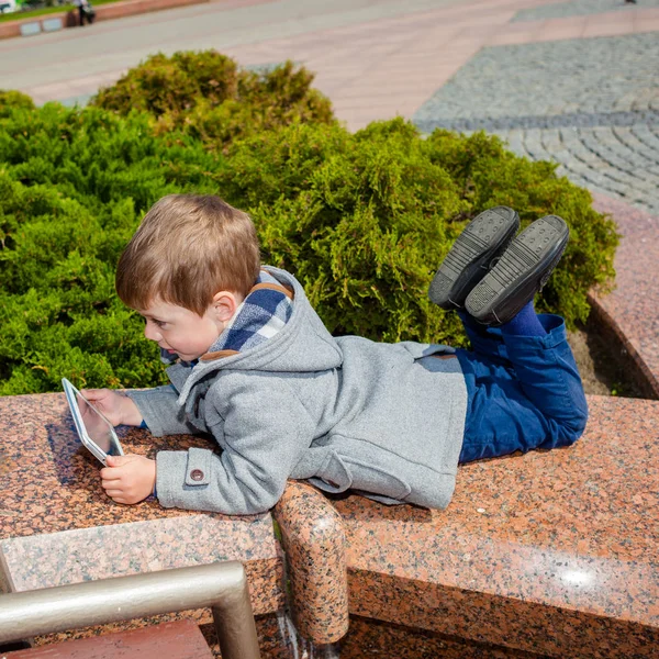 Petit garçon utilise une tablette à l'extérieur — Photo