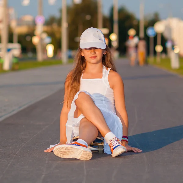 Девочка-подросток катается на скейтборде на вечерней улице — стоковое фото