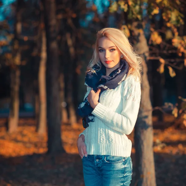 Bella ragazza bionda in un maglione bianco congelamento nel parco — Foto Stock