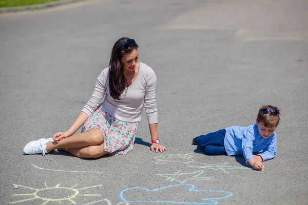 ママと小さな息子を道路にチョークで描く. — ストック写真