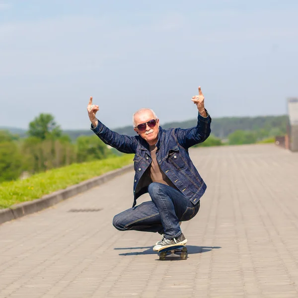 Enérgico homem sênior gostando de andar de skate — Fotografia de Stock