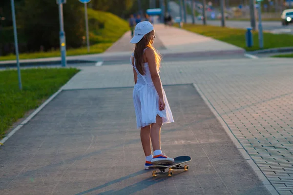 Девочка-подросток катается на скейтборде на вечерней улице — стоковое фото