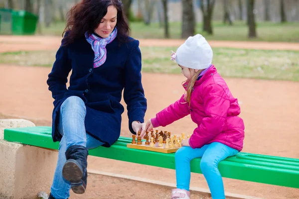 Mãe e filha jogando xadrez em um banco no parque — Fotografia de Stock
