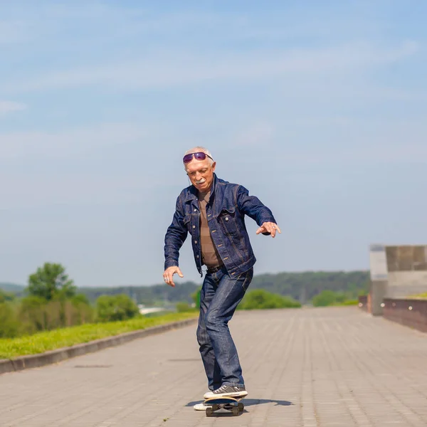 Enérgico homem sênior gostando de andar de skate — Fotografia de Stock