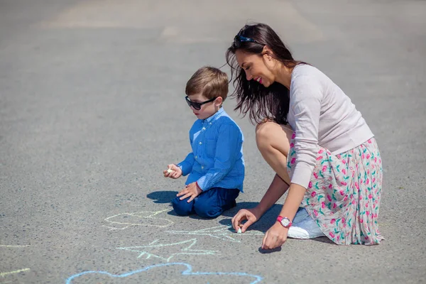 妈妈和小儿子用粉笔在马路上画线. — 图库照片