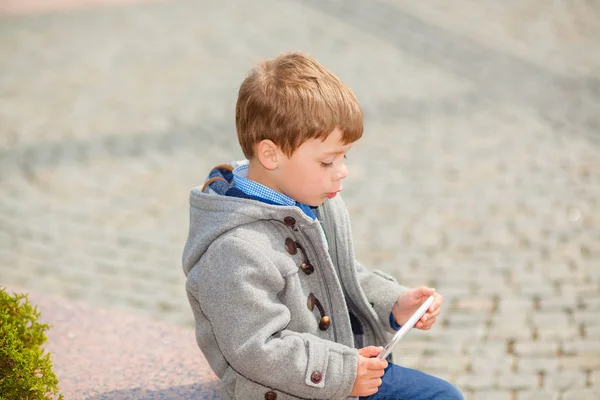 Маленький мальчик использует планшет на улице — стоковое фото