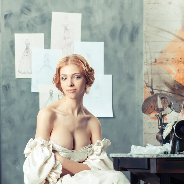 Mulher bonita em vestido vintage em estúdio de design de roupas — Fotografia de Stock