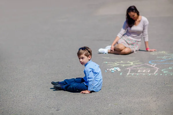 妈妈和小儿子用粉笔在马路上画线. — 图库照片