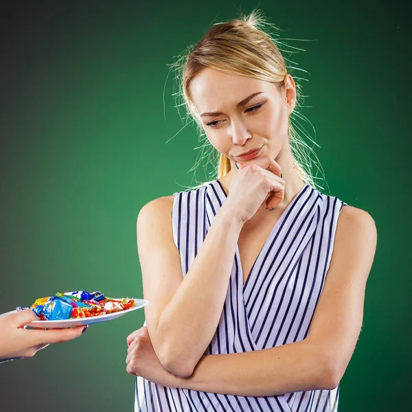 Frau zweifelt, ob sie Süßigkeiten isst oder nicht — Stockfoto