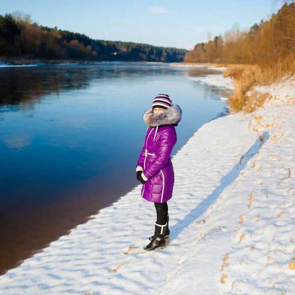 Adolescent fille marche en hiver sur la rive d'une rivière gelée — Photo