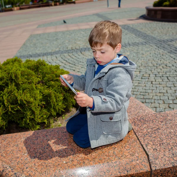 Маленький мальчик использует планшет на улице — стоковое фото