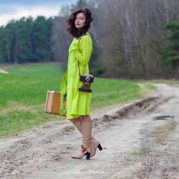 Хипстерская девушка с чемоданом и ретро-камерой на дороге — стоковое фото