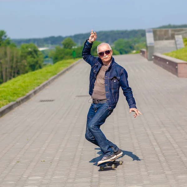 Enérgico homem sênior gostando de andar de skate — Fotografia de Stock