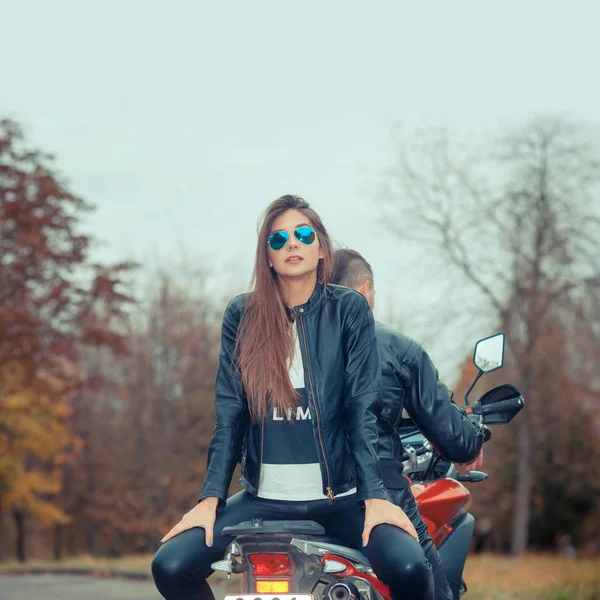 Beau couple avec une moto au coucher du soleil — Photo