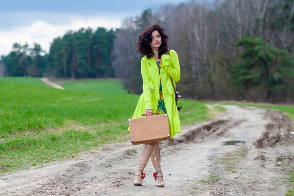 Hipster chica con una maleta y una cámara retro en la carretera — Foto de Stock