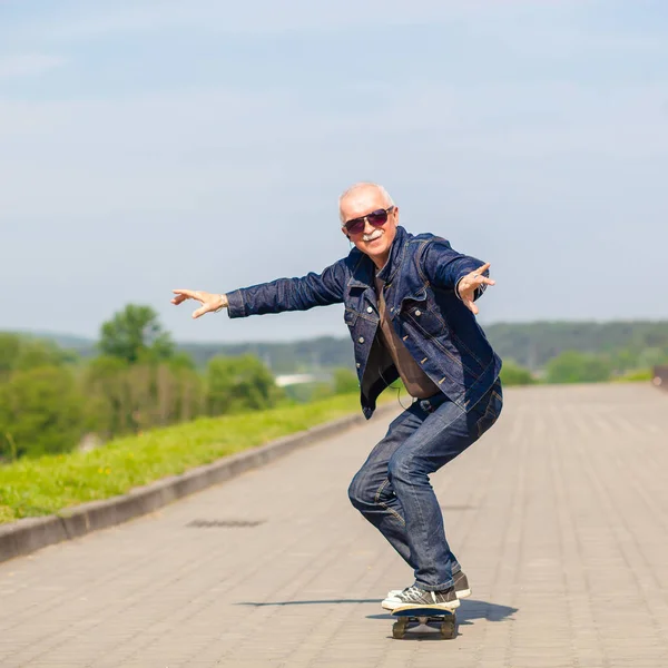 Energisk senior mannen njuter rida en skateboard — Stockfoto