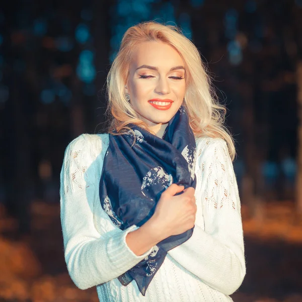 Schöne blonde Mädchen in einem weißen Pullover friert im Park — Stockfoto