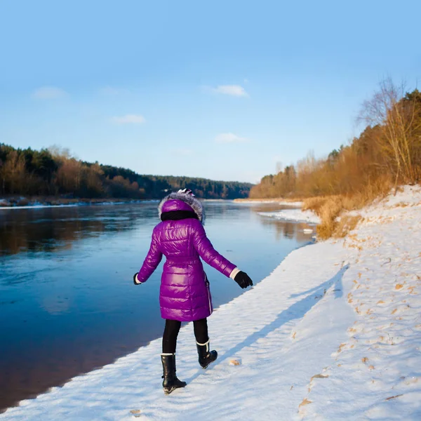 겨울에 얼어붙은 강의 은행에 산책 하는 십 대 소녀 로열티 프리 스톡 사진