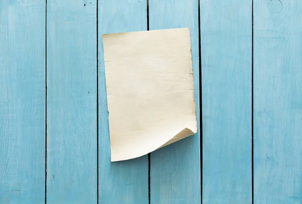 Старая бумага на голубой деревянной стене — стоковое фото