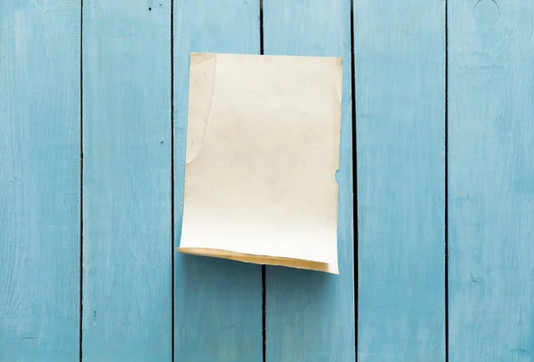 Старая бумага на голубой стене — стоковое фото