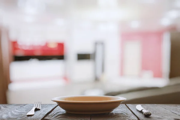 Пустая тарелка с вилкой и ножом на деревянном столе — стоковое фото